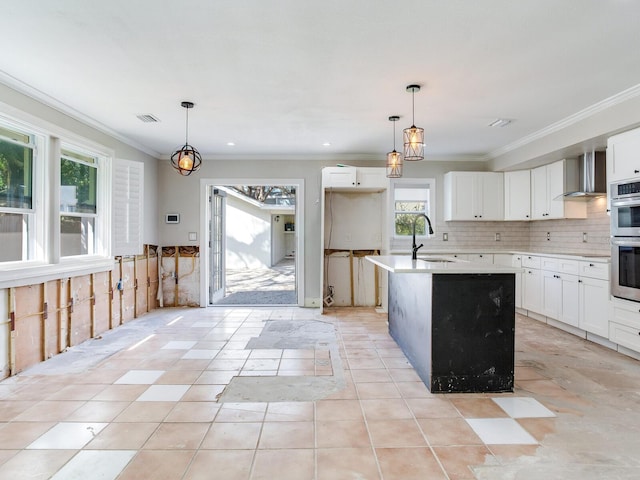 kitchen featuring tasteful backsplash, visible vents, crown molding, wall chimney exhaust hood, and a sink