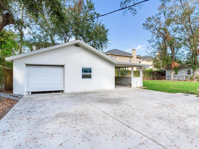 view of property exterior with stucco siding, driveway, a yard, and fence