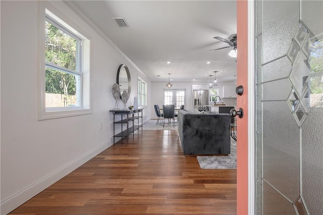 interior space with visible vents, baseboards, dark wood-style flooring, a sink, and crown molding