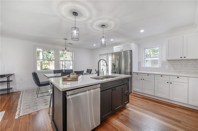 kitchen with tasteful backsplash, light countertops, hardwood / wood-style floors, appliances with stainless steel finishes, and a sink