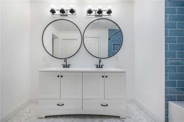 full bathroom with double vanity, baseboards, and a sink