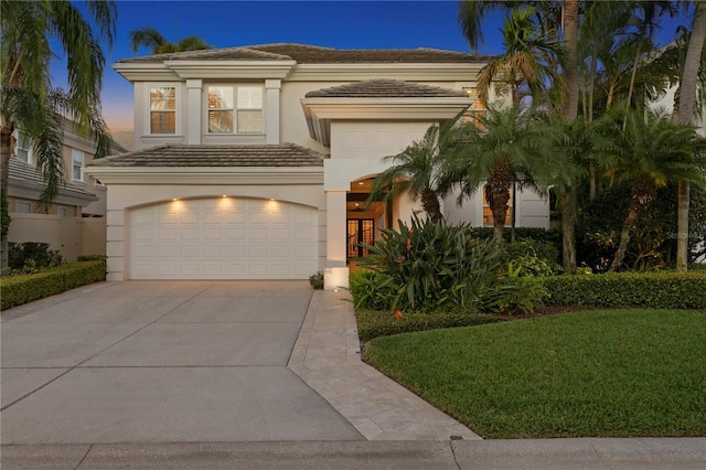 view of front of home featuring a tile roof, concrete driveway, stucco siding, a yard, and an attached garage