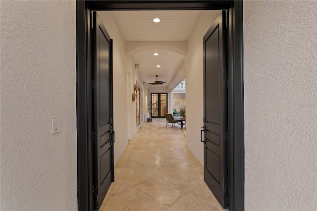 hallway with recessed lighting, arched walkways, and a textured wall