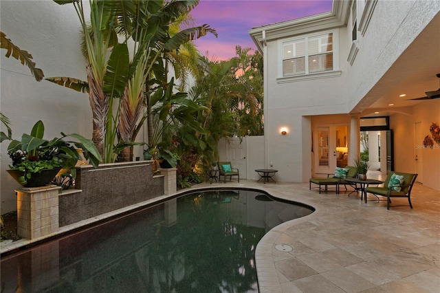 pool at dusk with a fenced in pool, a patio area, and fence