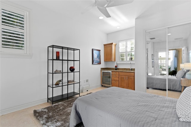 bedroom featuring light tile patterned floors, baseboards, a sink, wine cooler, and a closet