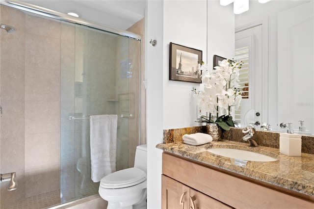 bathroom with a shower stall, toilet, and vanity