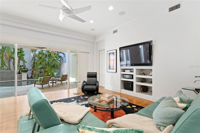 living area featuring visible vents, ornamental molding, ceiling fan, and wood finished floors