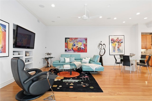 living area featuring crown molding, baseboards, light wood-type flooring, and ceiling fan