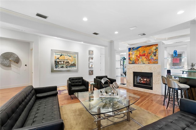 living room featuring wood finished floors, visible vents, recessed lighting, ornamental molding, and a glass covered fireplace