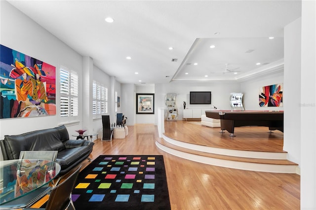 playroom with a ceiling fan, a tray ceiling, wood finished floors, recessed lighting, and baseboards