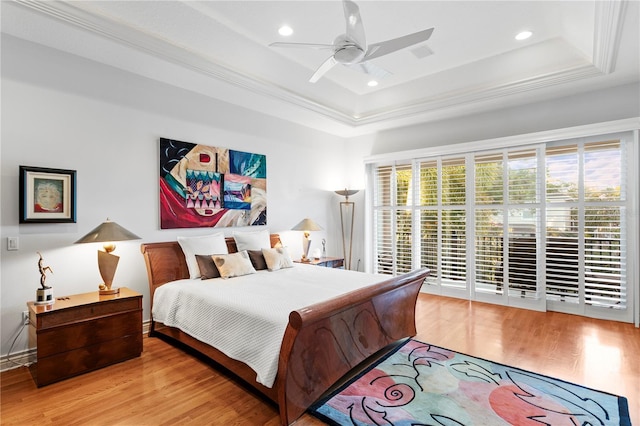 bedroom featuring a raised ceiling, recessed lighting, and wood finished floors