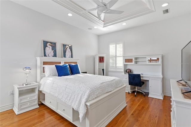 bedroom with recessed lighting, light wood-style floors, and a tray ceiling