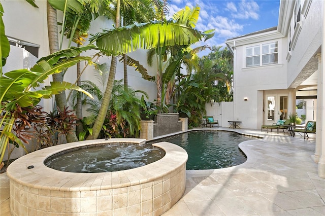 pool featuring fence, an in ground hot tub, and a patio area