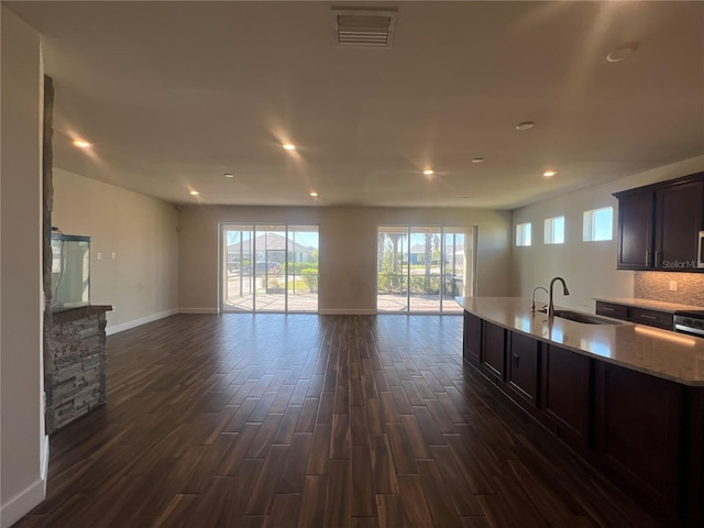 kitchen with visible vents, dark wood finished floors, dark brown cabinetry, open floor plan, and a sink