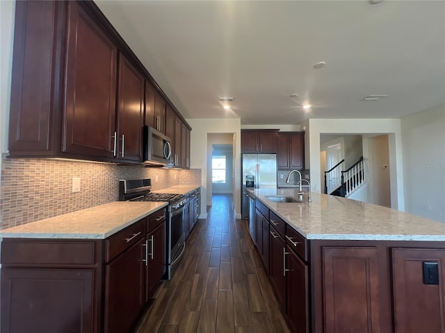 kitchen with a sink, stainless steel appliances, dark brown cabinetry, decorative backsplash, and dark wood-style flooring