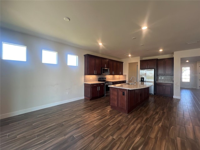 kitchen featuring a sink, backsplash, dark wood finished floors, stainless steel appliances, and light countertops