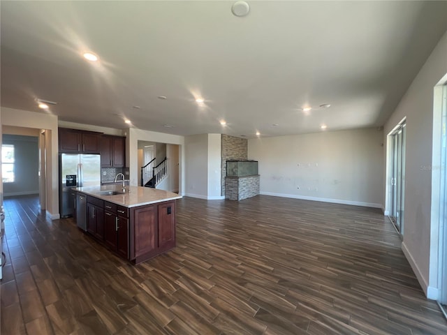 kitchen featuring open floor plan, light countertops, dark wood-style floors, stainless steel fridge, and a sink