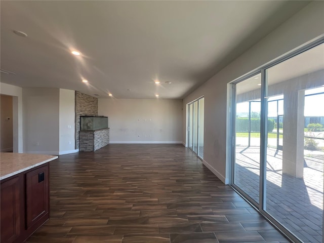 unfurnished living room with recessed lighting, baseboards, dark wood-style floors, and a fireplace