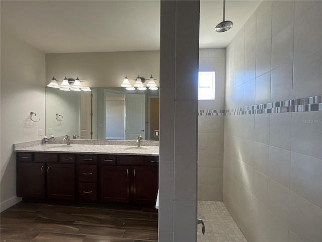 bathroom with double vanity, a tile shower, and a sink