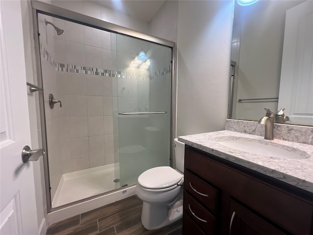 full bath with a shower stall, toilet, vanity, and wood finished floors