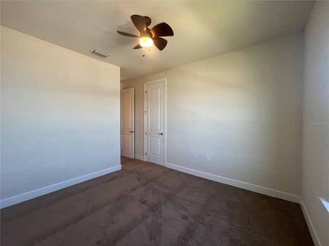 empty room with visible vents, baseboards, a ceiling fan, and dark carpet