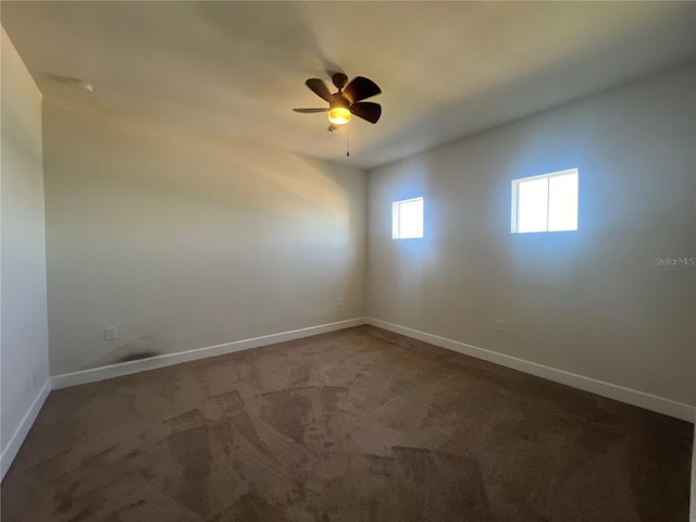 carpeted empty room featuring baseboards and a ceiling fan