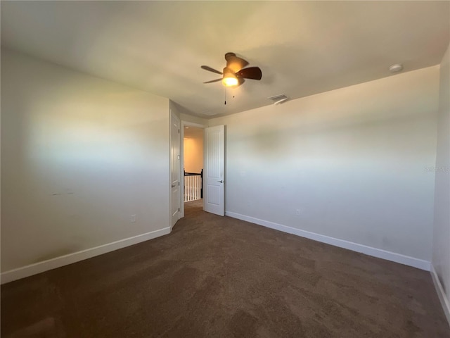 unfurnished room with dark colored carpet, visible vents, baseboards, and ceiling fan