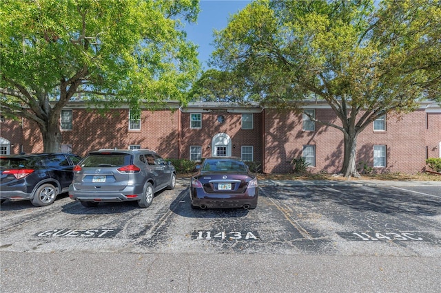 view of property with uncovered parking and brick siding