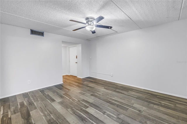 spare room featuring visible vents, baseboards, ceiling fan, wood finished floors, and a textured ceiling