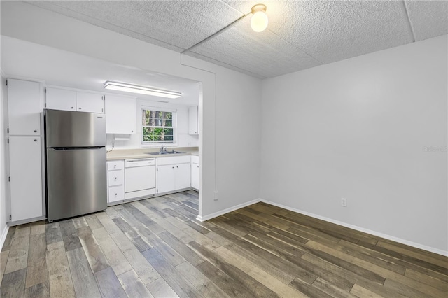 kitchen with light countertops, freestanding refrigerator, wood finished floors, white cabinetry, and white dishwasher