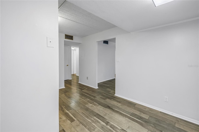 spare room featuring visible vents, a textured ceiling, baseboards, and wood finished floors