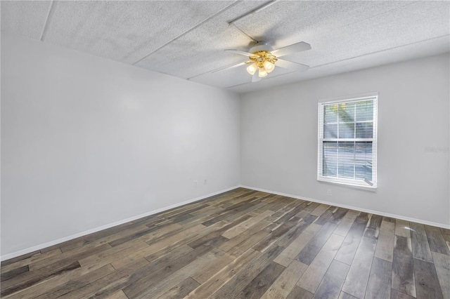 spare room with baseboards, dark wood-type flooring, ceiling fan, and a textured ceiling