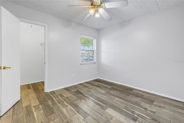 unfurnished room with baseboards, a textured ceiling, ceiling fan, and wood finished floors