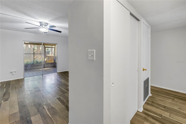 hall featuring baseboards, a textured ceiling, and wood finished floors