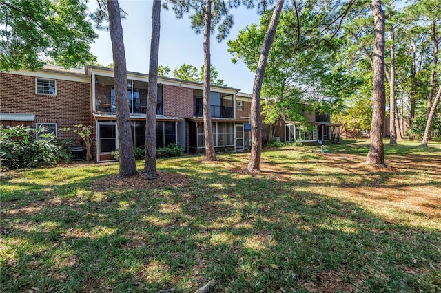 rear view of property featuring a lawn and brick siding