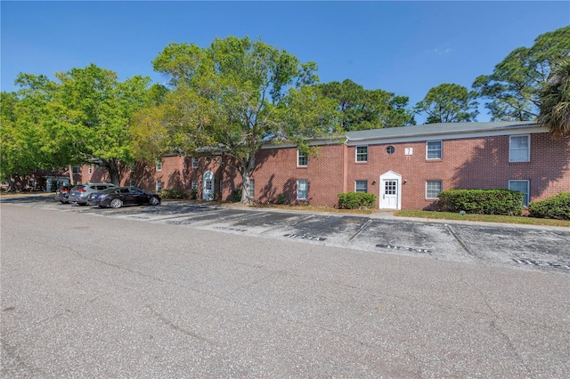 multi unit property with brick siding and uncovered parking