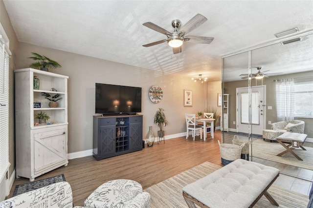 living area featuring wood finished floors, a ceiling fan, visible vents, and baseboards