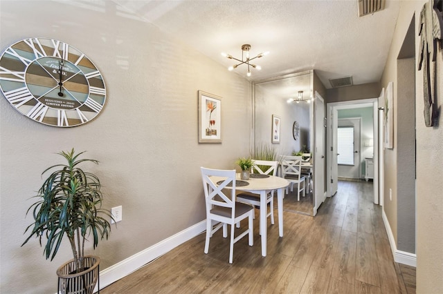 dining space with visible vents, baseboards, a notable chandelier, and wood finished floors