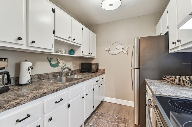 kitchen featuring light wood finished floors, black microwave, electric stove, white cabinets, and a sink