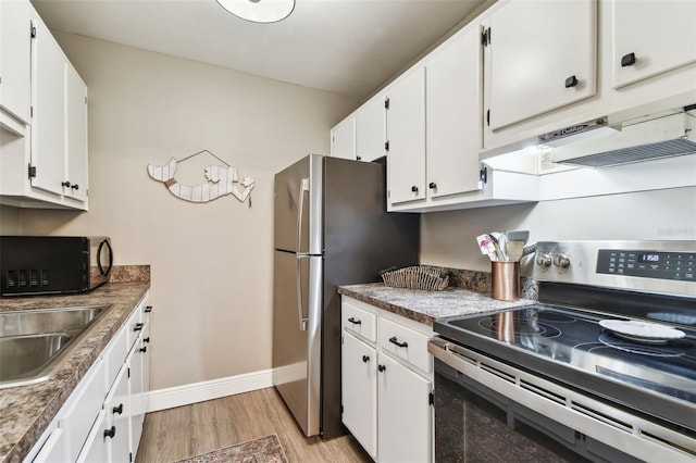 kitchen featuring baseboards, under cabinet range hood, light wood-type flooring, appliances with stainless steel finishes, and white cabinets