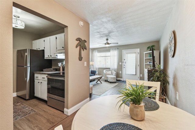 kitchen featuring ceiling fan, stainless steel appliances, wood finished floors, white cabinets, and a textured ceiling