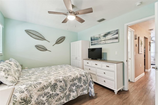 bedroom with a ceiling fan, wood finished floors, visible vents, and baseboards