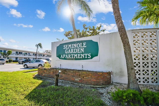 community sign featuring a yard and uncovered parking