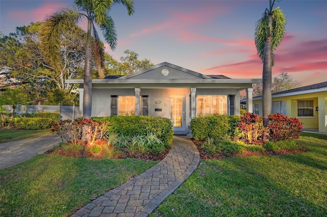 view of front of property with stucco siding, a front yard, and fence