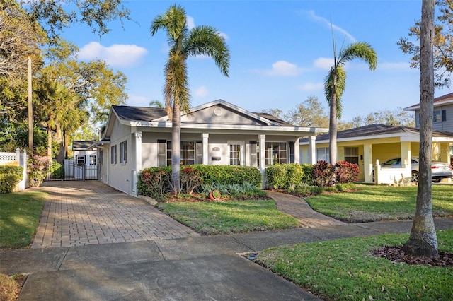 view of front facade featuring a front yard, a gate, fence, driveway, and stucco siding