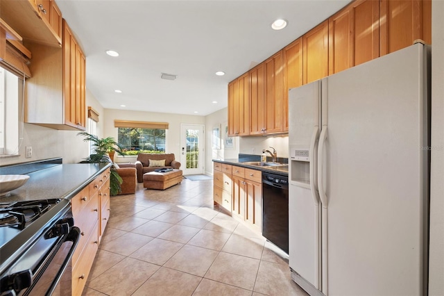 kitchen featuring a sink, range with gas stovetop, dark countertops, white refrigerator with ice dispenser, and dishwasher