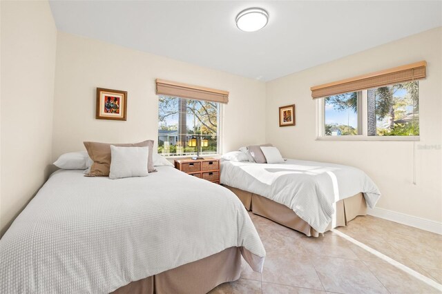 bedroom with baseboards, multiple windows, and light tile patterned flooring