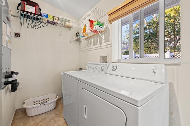 laundry area with washing machine and clothes dryer, laundry area, baseboards, and light tile patterned floors