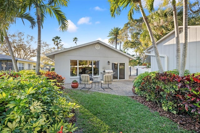 back of property featuring a patio area, a lawn, stucco siding, and fence