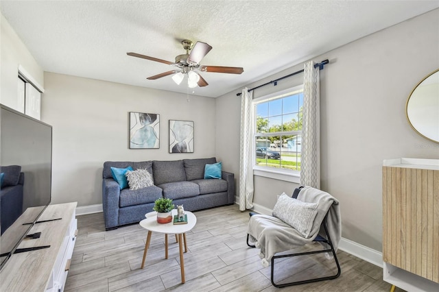 living area featuring baseboards, ceiling fan, radiator heating unit, light wood-style flooring, and a textured ceiling